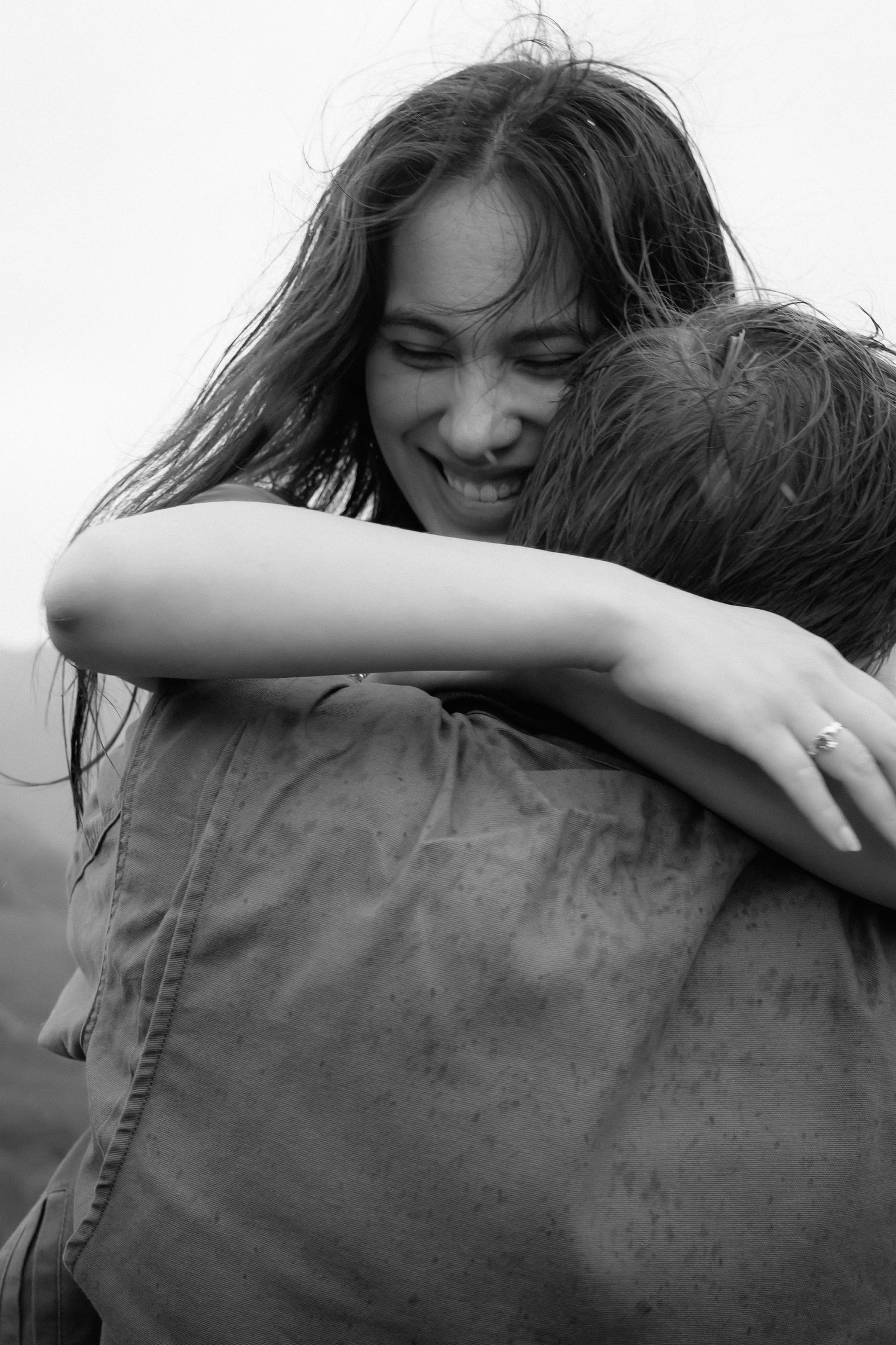 A black and white intimate portrait of a couple embracing in a tender moment as they smile and hug.