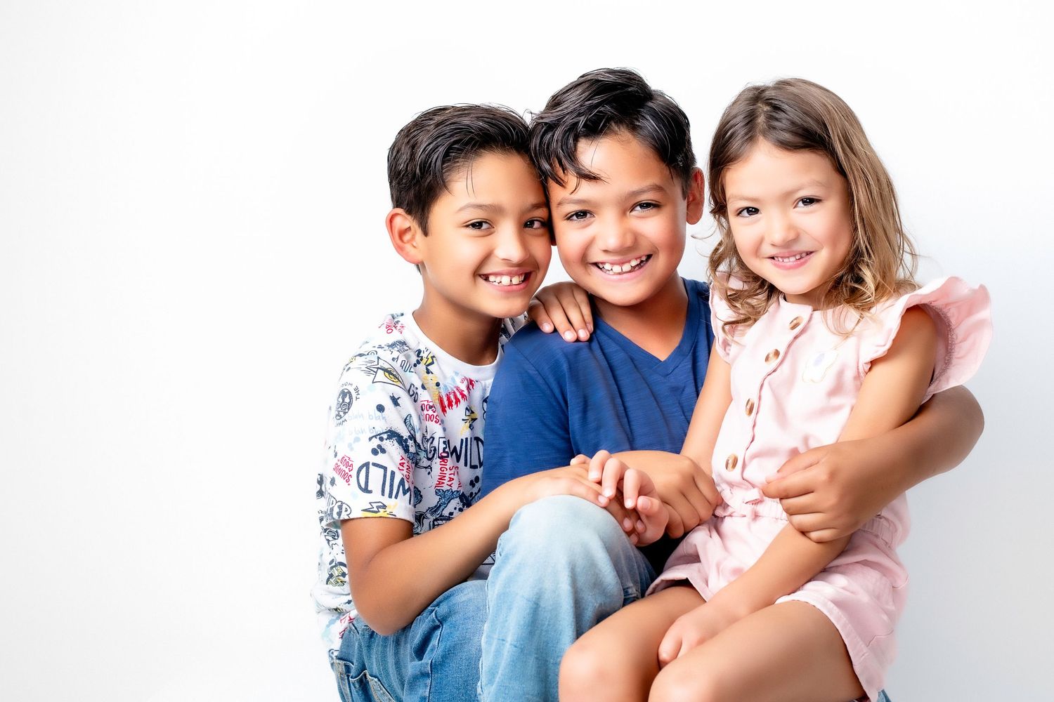 Happy group of people hugging and laughing together while sitting on a white couch.