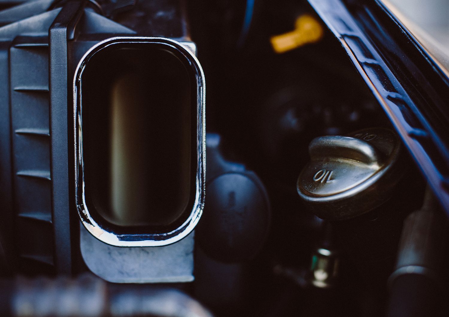 Close up view of a chrome truck mirror and dark vehicle interior with steering wheel visible in background.