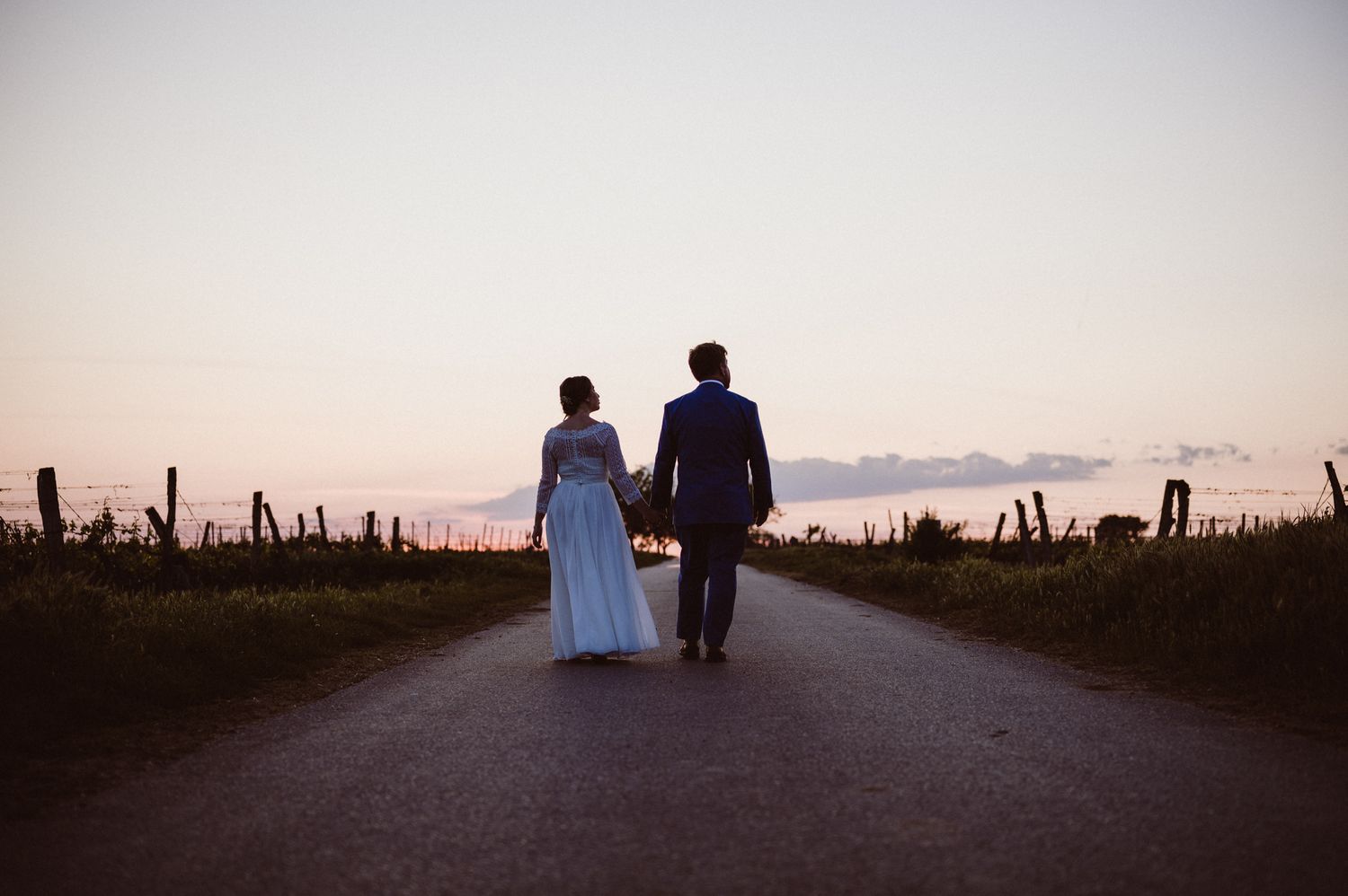 Two silhouetted figures walking on a sunset path create a romantic atmosphere against a dreamy pink sky.