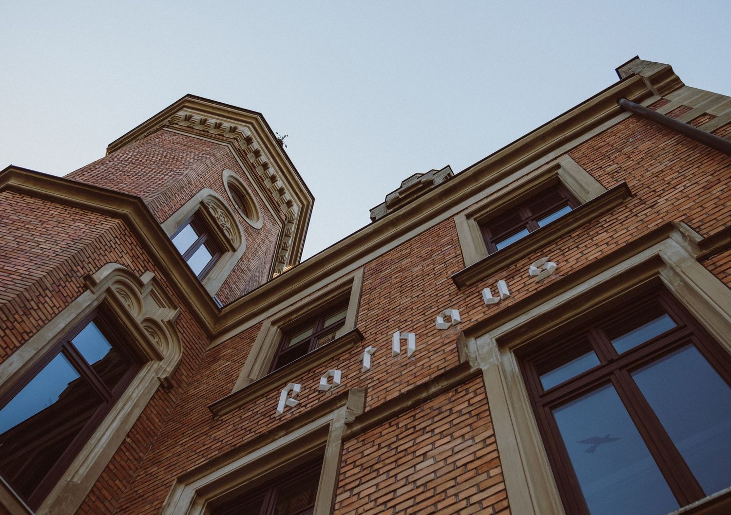 Low angle view of historic red brick building facade with ornate architectural details and pointed windows.