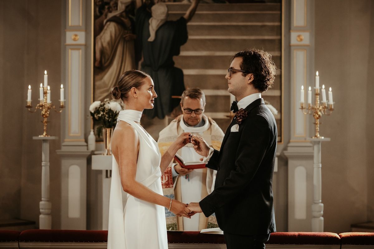 Stiligt brudpar växlar ringar under deras vigselceremoni i släps kyrka. Foto av Grevholm Photography