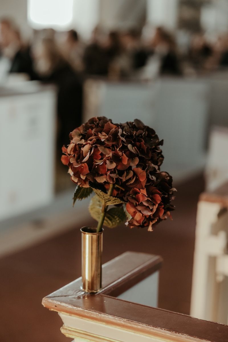 En dekorativ röd hortensia i en kyrka under ett bröllop. Foto av Grevholm Photography