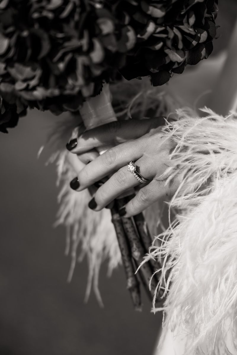 Närbild på brudens vigselring som gnistrar i solen när hon håller i sin brudbukett av hortensior. Foto av Grevholm Photography
