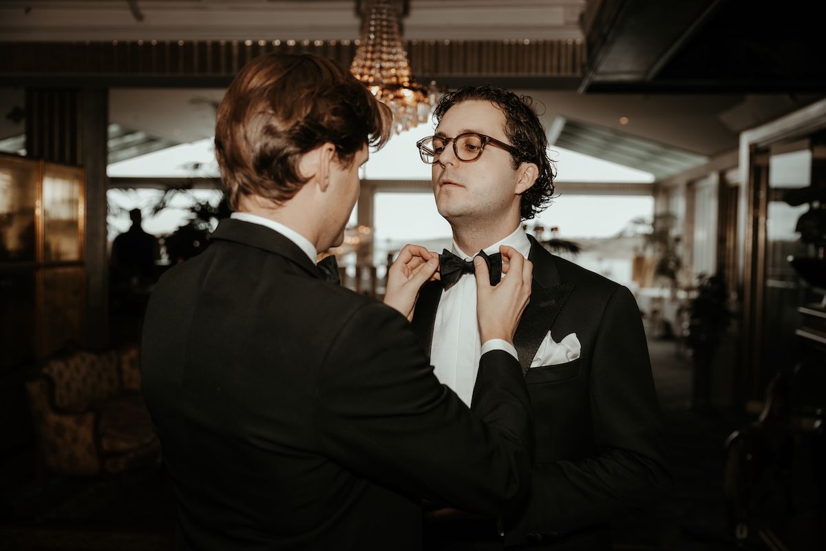 Best man rättar till flugan på brudgummen under förberedelserna inför ett bröllop på västkusten. Foto av Grevholm Photography