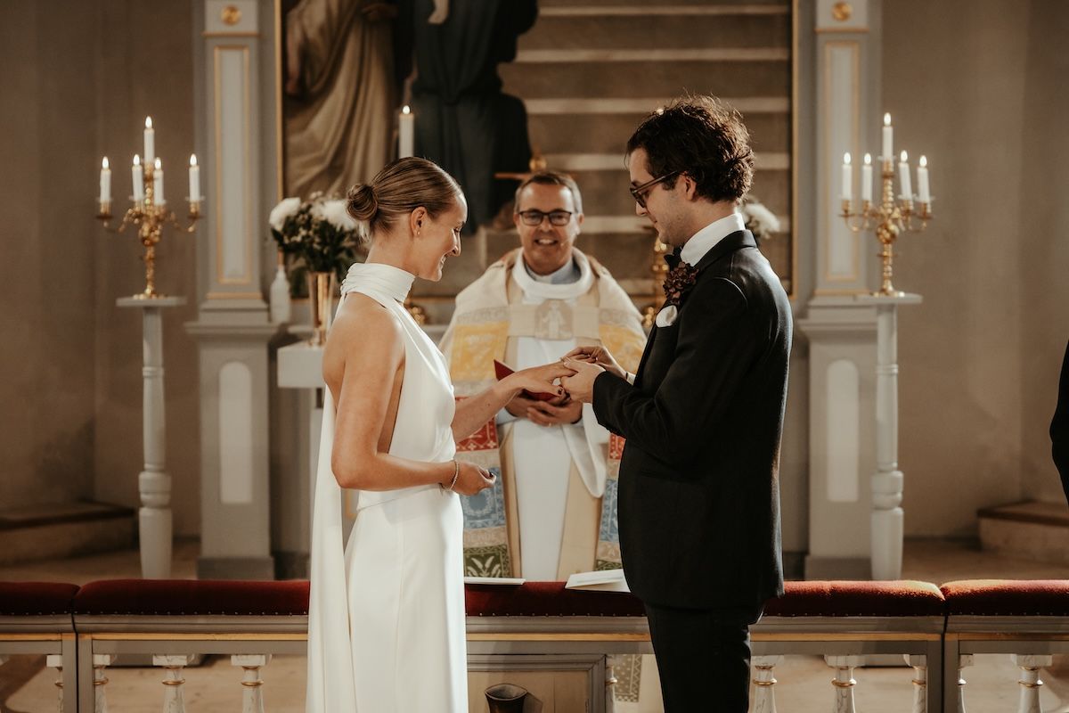 Stiligt brudpar växlar ringar under deras vigselceremoni i släps kyrka. Foto av Grevholm Photography