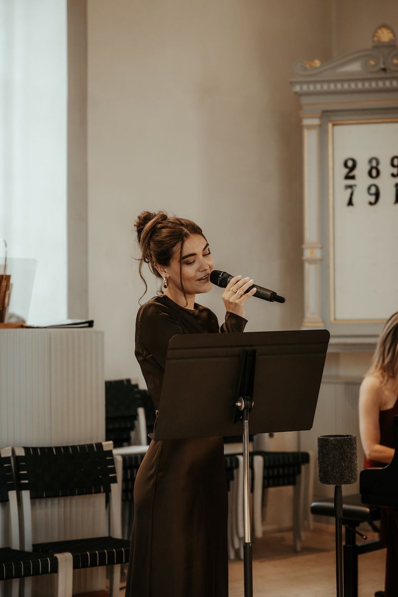 En solist sjunger i en kyrka under ett bröllop på västkusten. Foto av Grevholm Photography