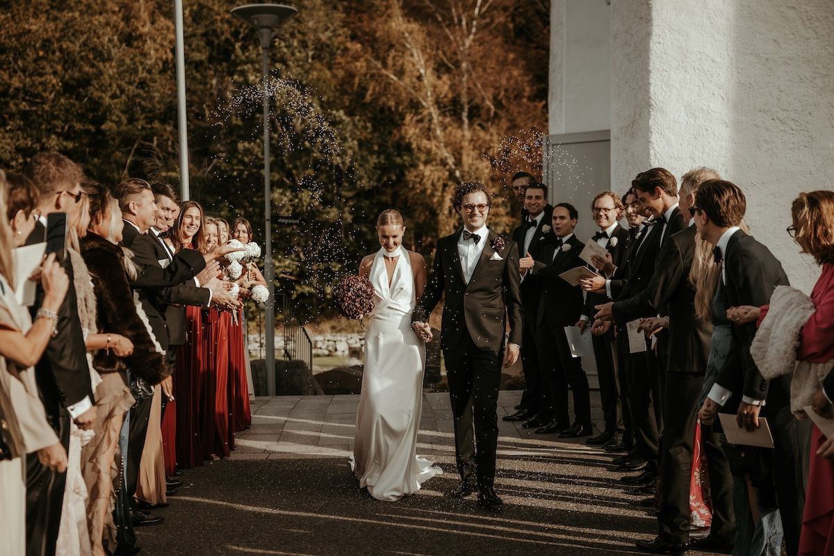 Brudpar tar emot jubel och gratulationer av sina gäster som kastar ris på dem när de går ut från kyrkan efter deras vigsel i Släps kyrka.