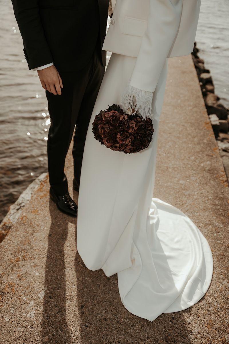 Close-up shots of a bride in a white wedding dress and groom in black suit walking together along a waterfront path.