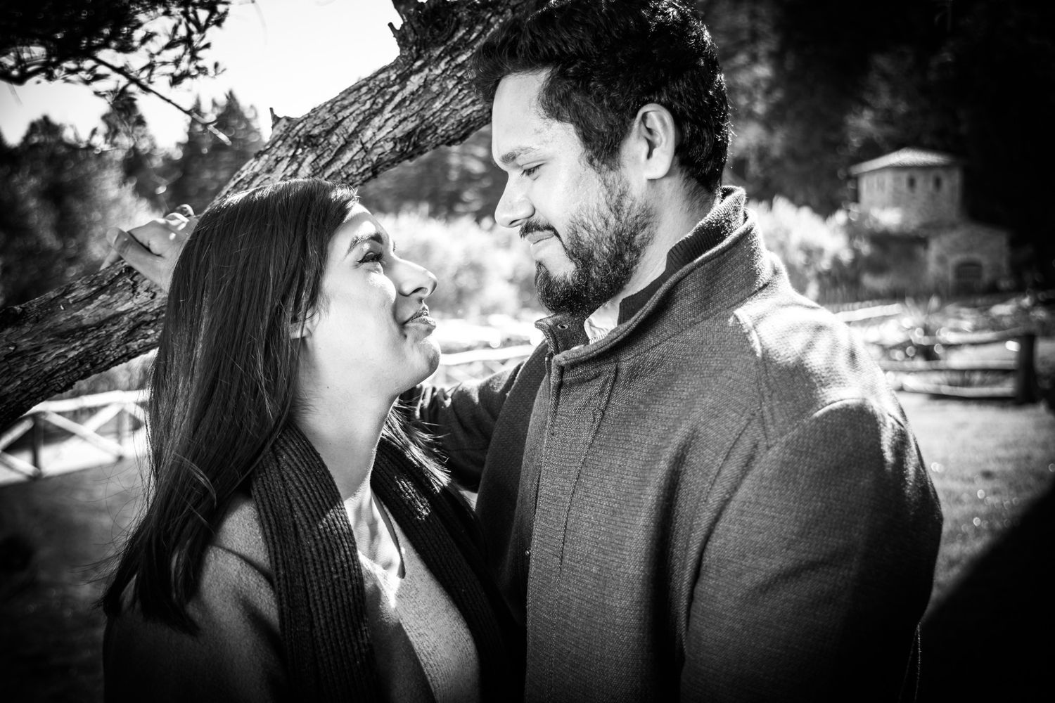 A romantic black and white portrait of a couple sharing an intimate moment outdoors.