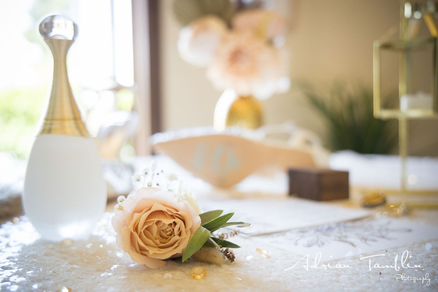 Peach rose and perfume bottle arranged on table with elegant wedding details.