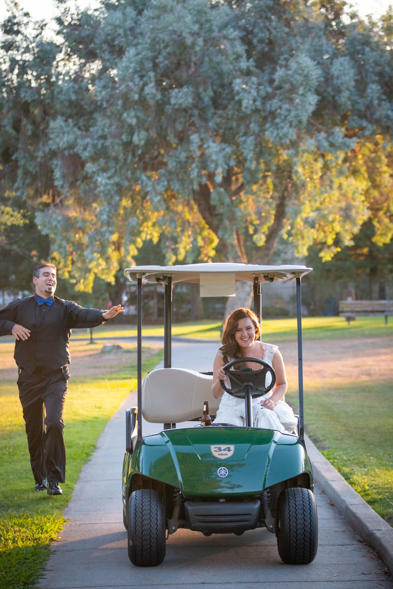 Couple enjoying a playful moment with a golf cart on a sunny path.