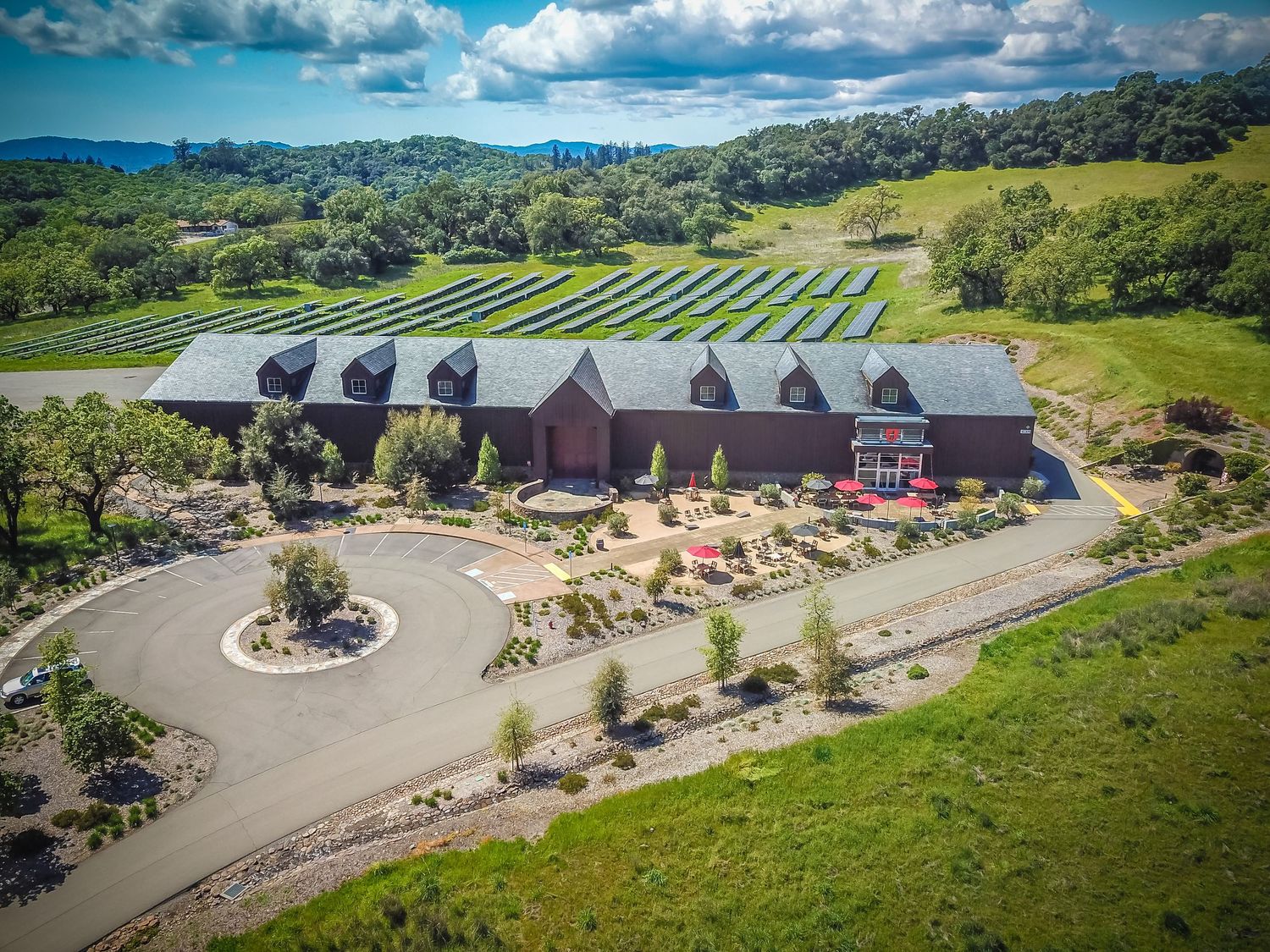 Modern winery complex with barrel-shaped buildings arranged in a curved layout.