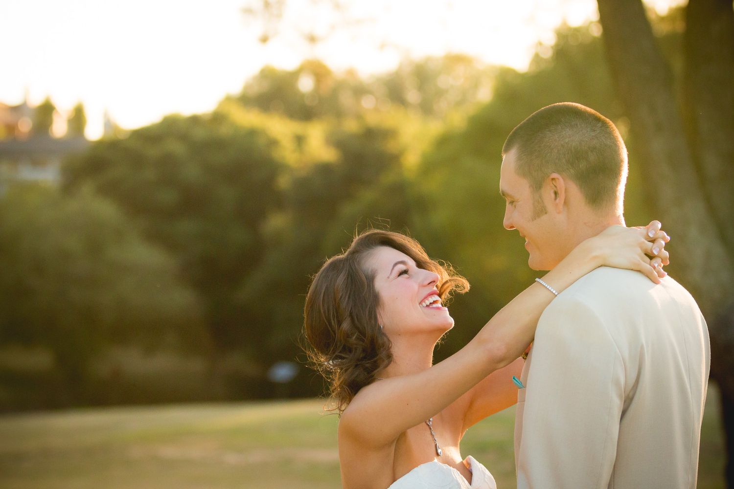 A joyful couple embraces outdoors during golden hour sunset.