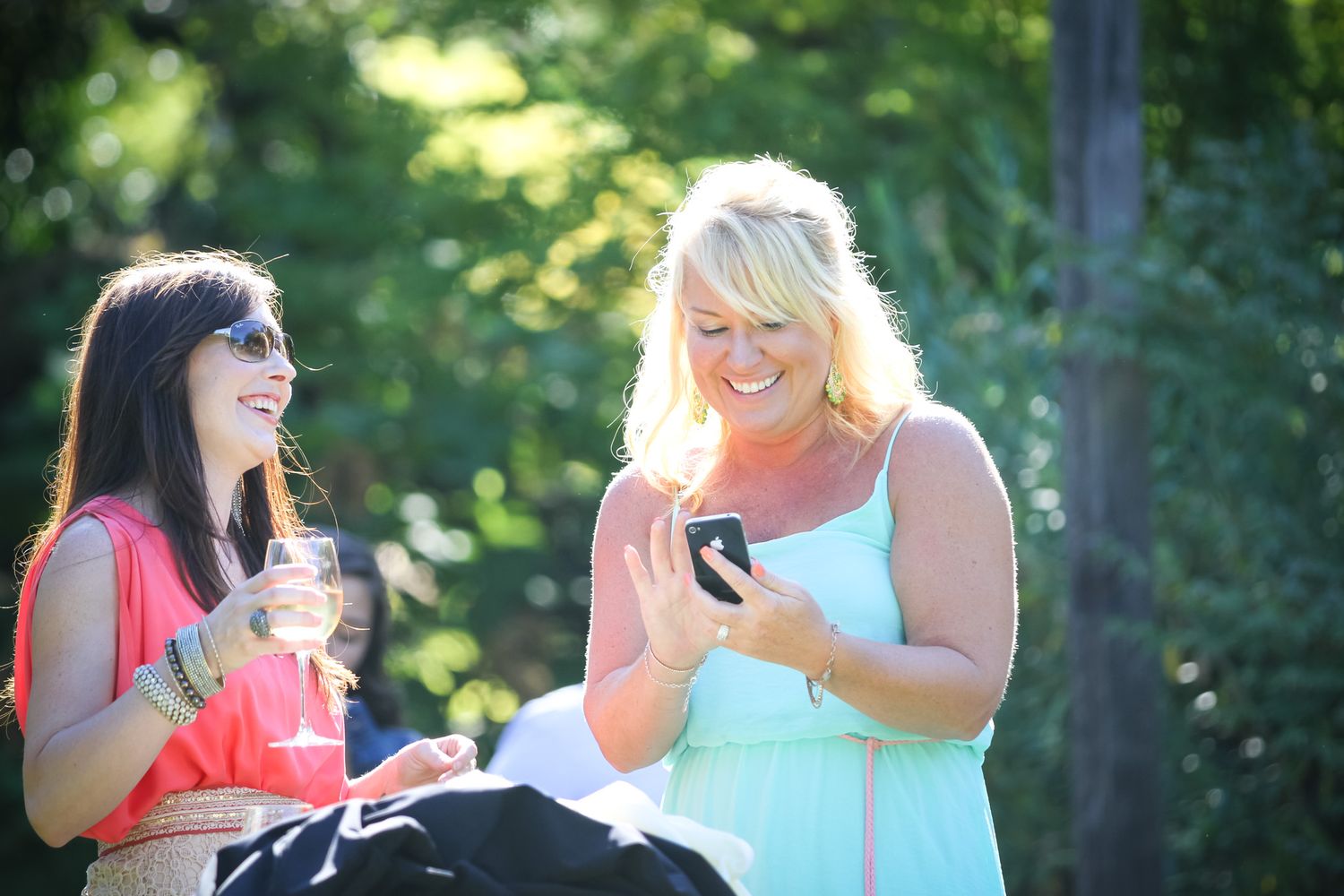 Wine enthusiasts sharing laughs during outdoor tasting session.