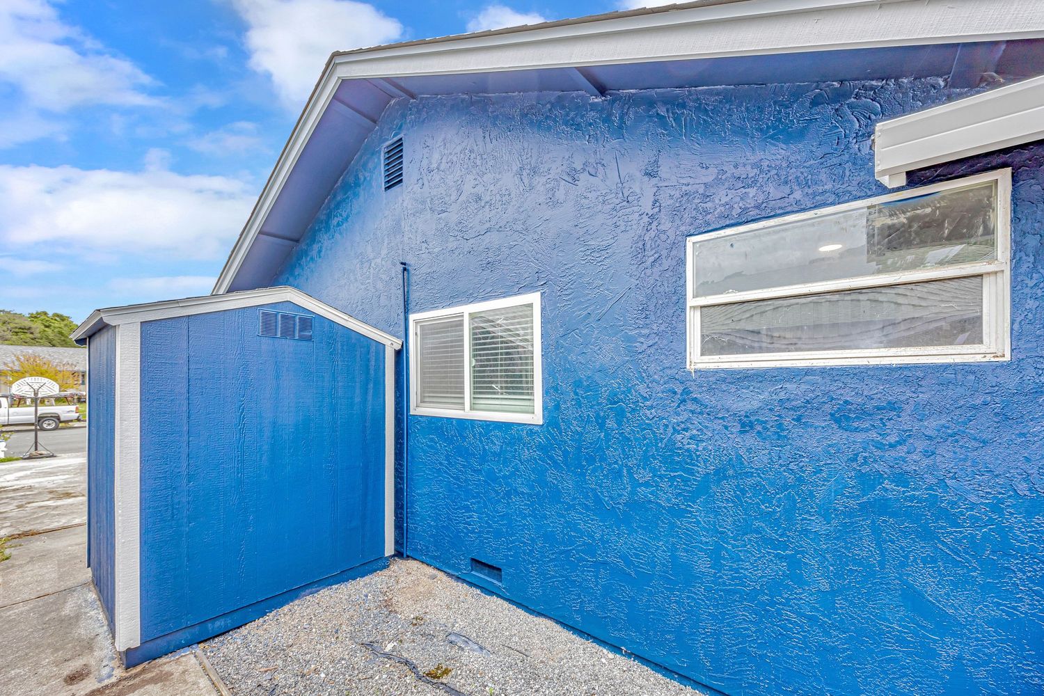Close-up of bright blue exterior wall with white windows and matching blue door.