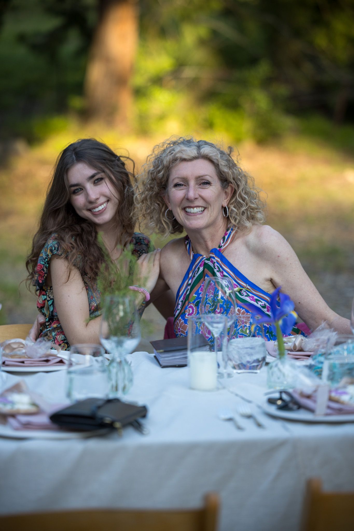 Two people enjoying outdoor dining at elegant table setting in garden atmosphere.