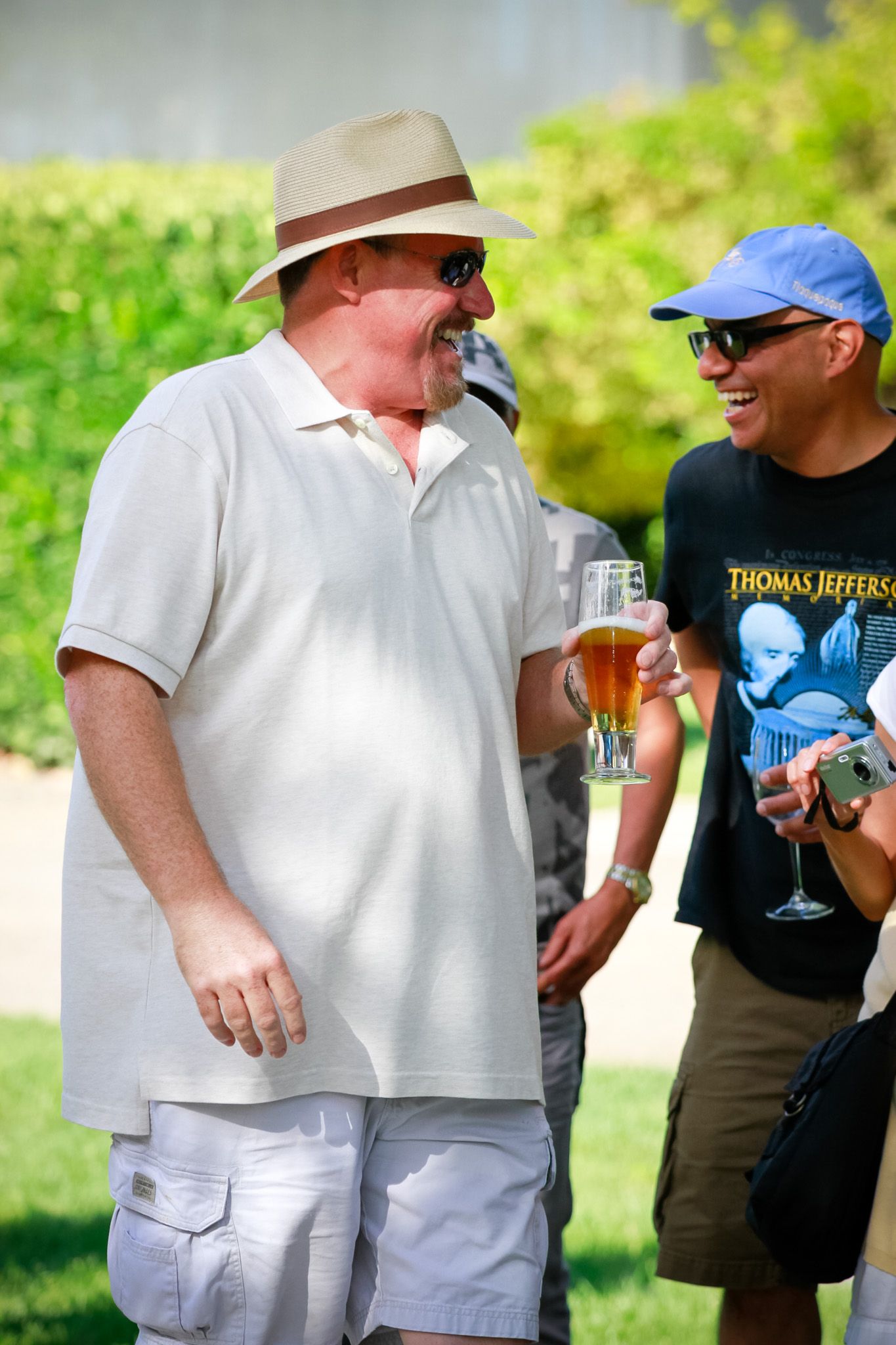 Two people sharing laughs while enjoying beverages at outdoor gathering.