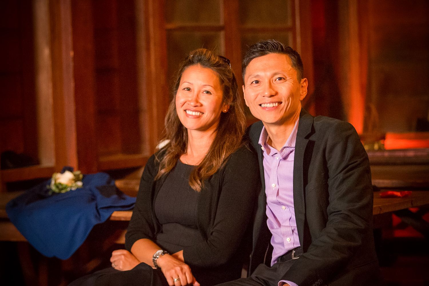 A couple smiles while sitting together at an evening event.