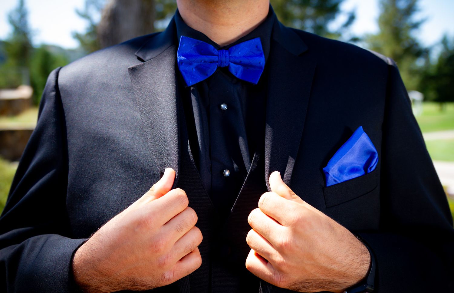 Detail shot of a formal suit with bright blue bowtie and matching pocket square.