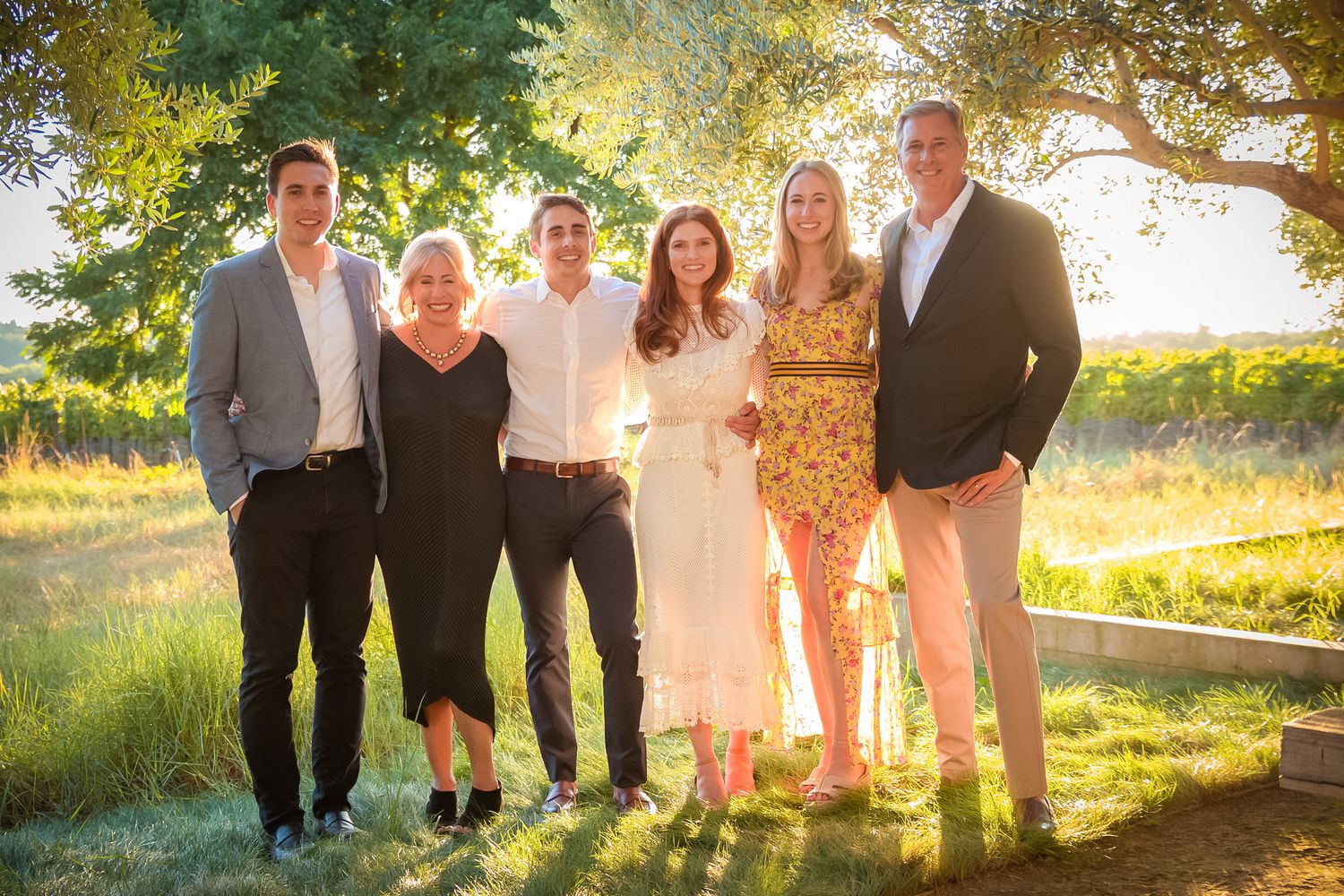 Family group photo at sunset with golden backlight through trees.
