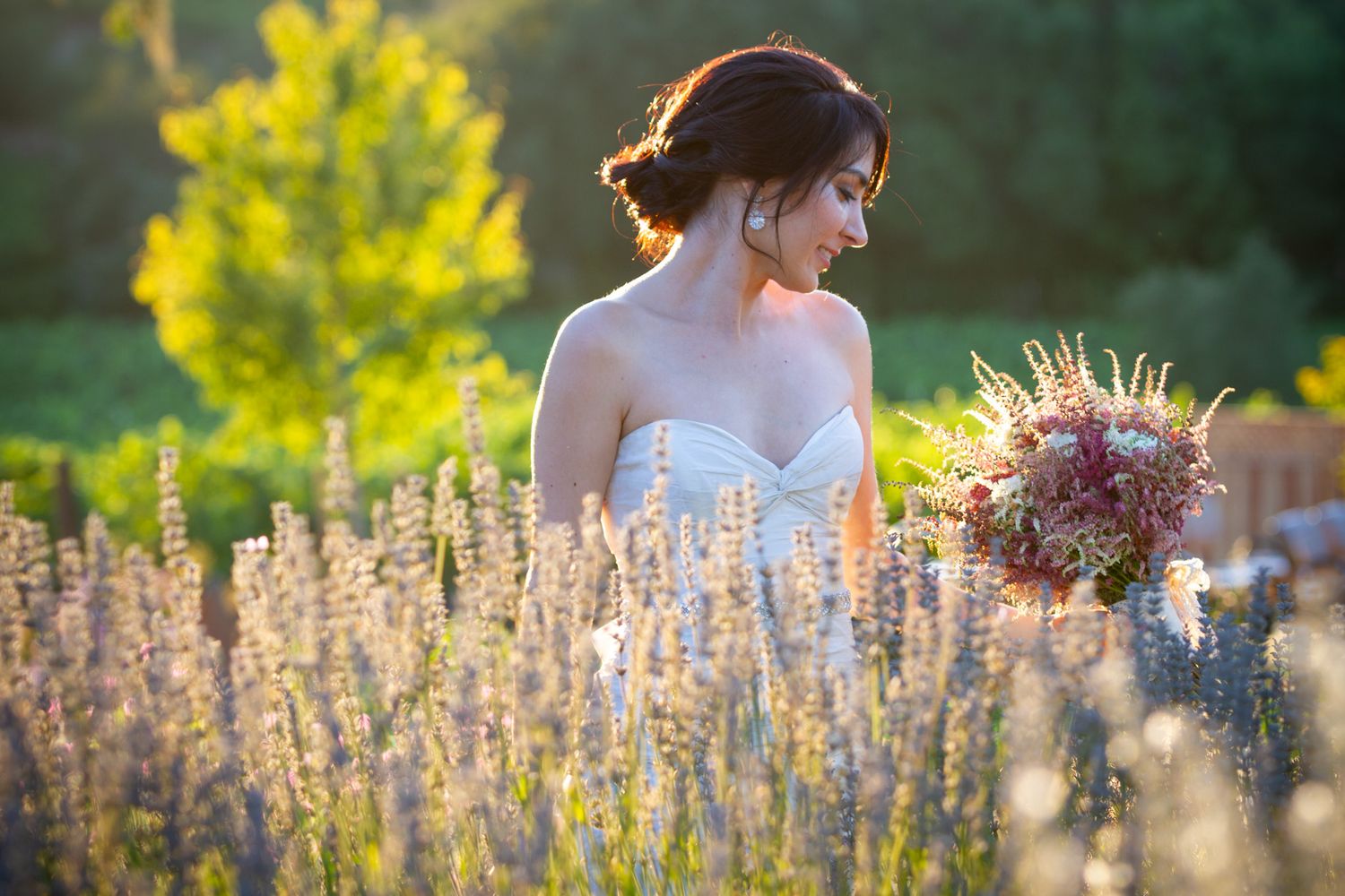 White strapless dress and wildflower bouquet amid sunlit lavender field at golden hour.