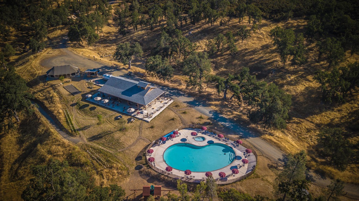 Luxury resort property with circular swimming pool and modern architecture viewed from above.