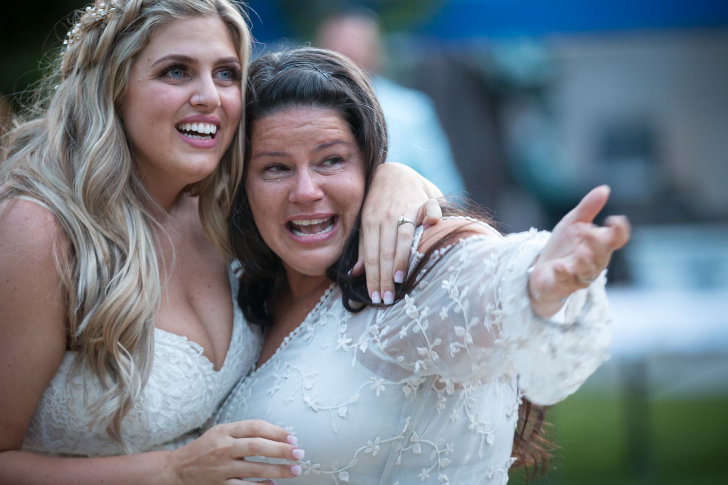 Two wedding guests share an enthusiastic moment of celebration outdoors.
