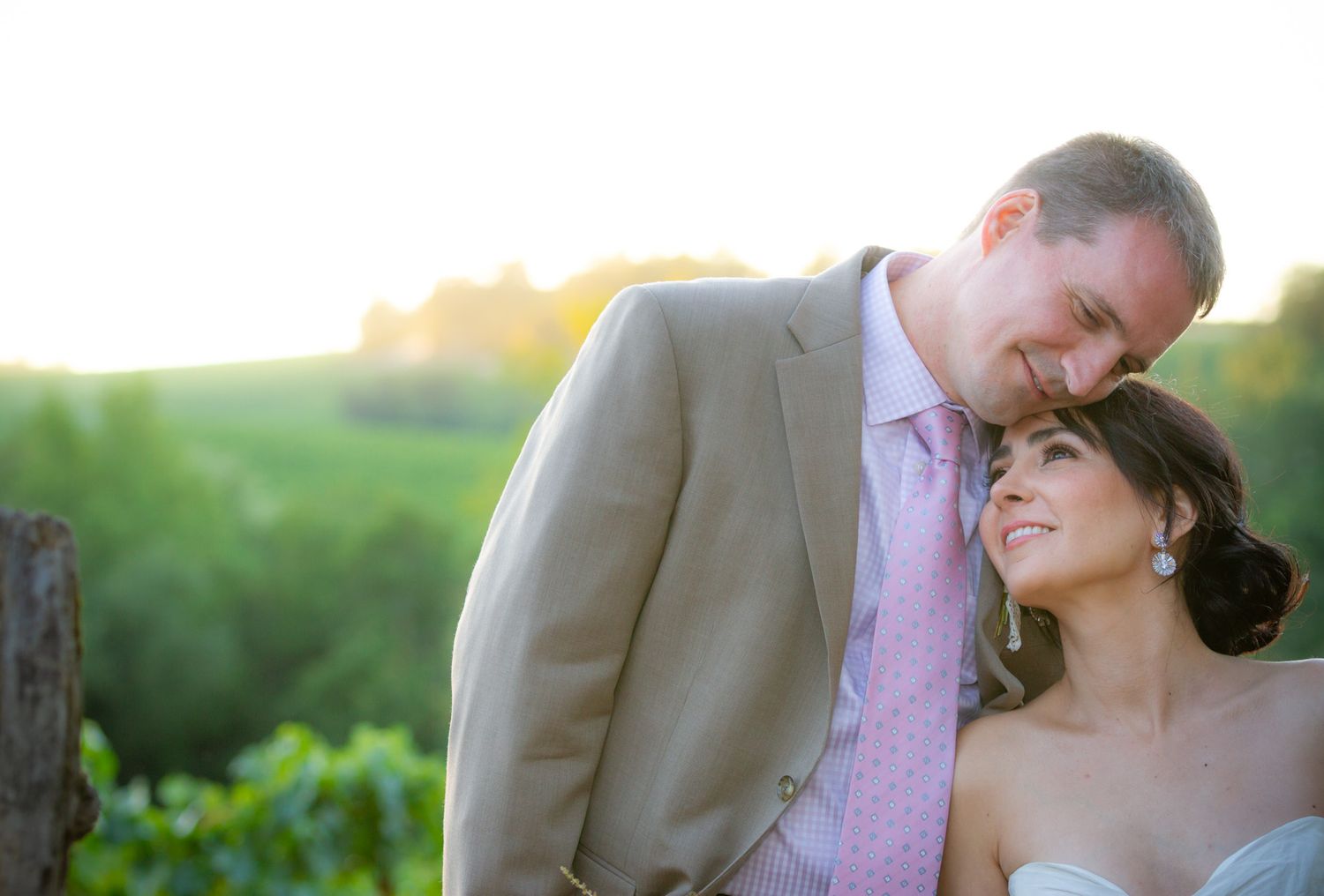 Intimate wedding portrait of couple embracing at sunset in garden setting.