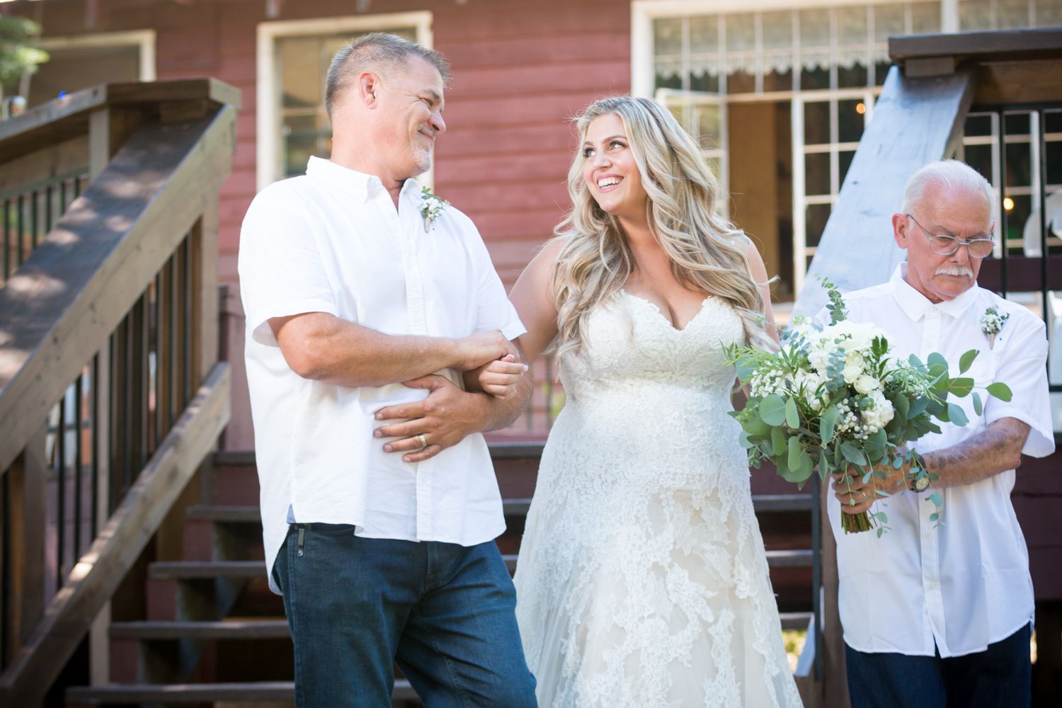Outdoor wedding ceremony in front of red building with wooden stairs.
