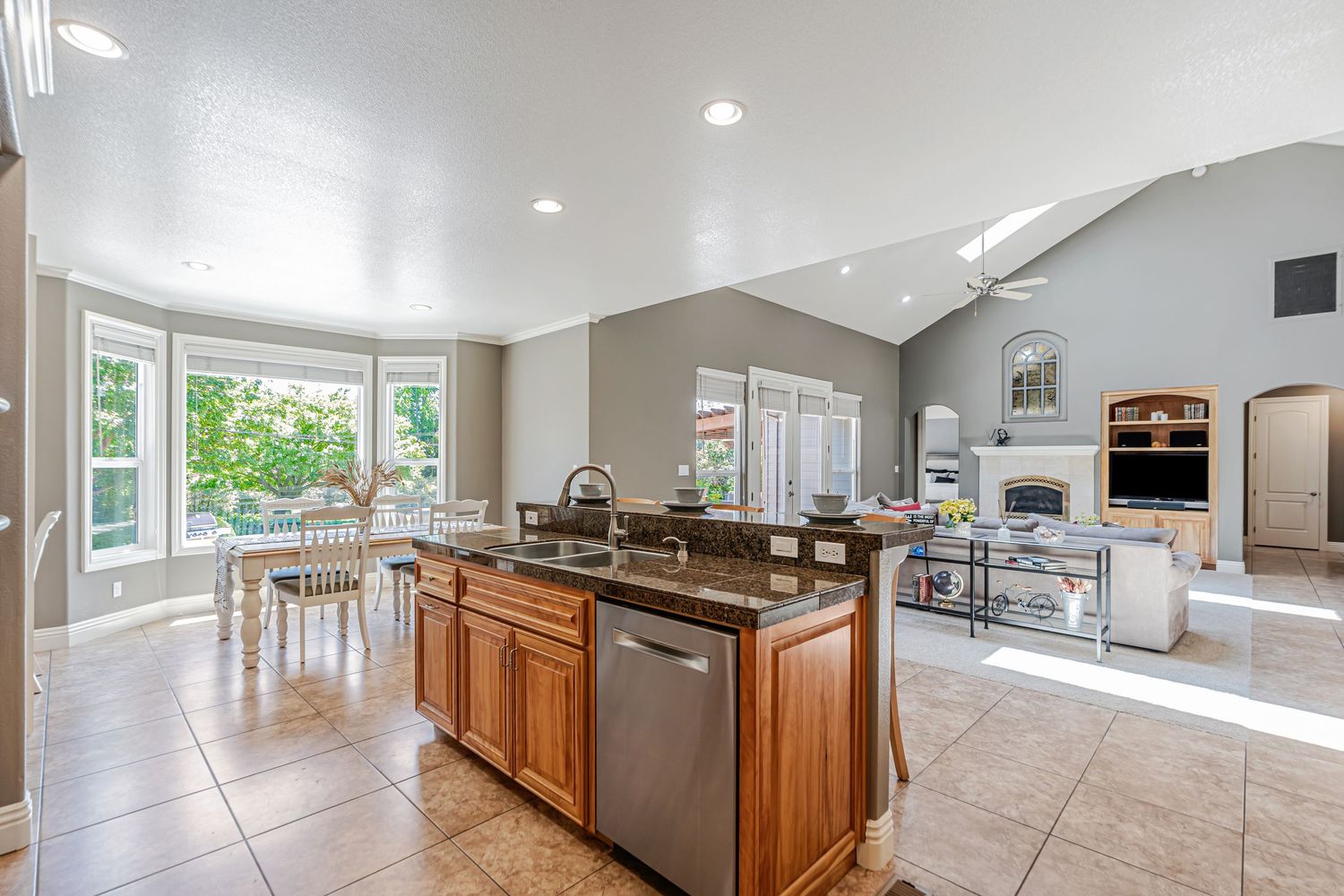 Modern kitchen with center island overlooking bright dining area and living space with vaulted ceilings.