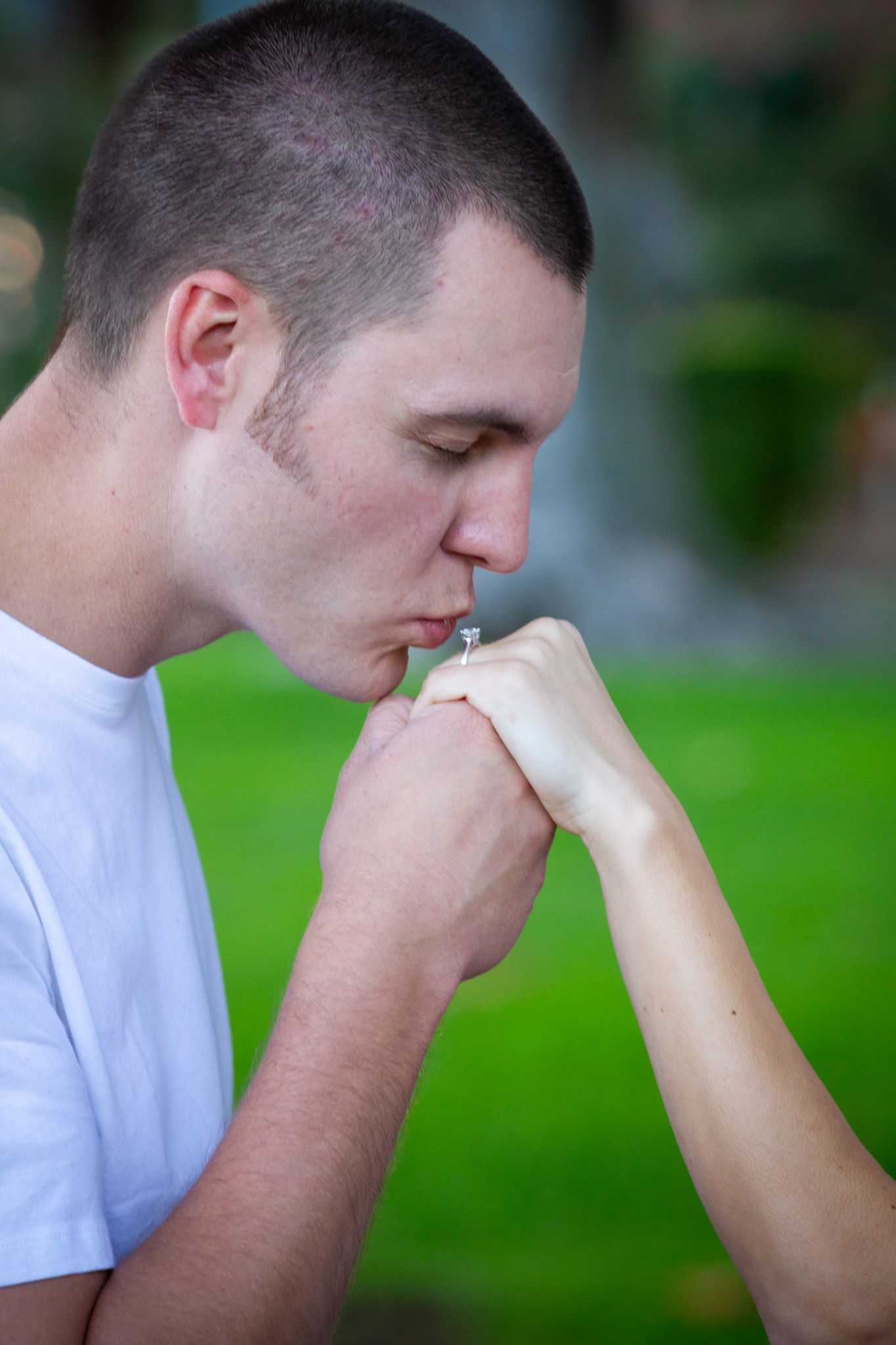 Person in a white t-shirt shown in profile view against a blurred background.