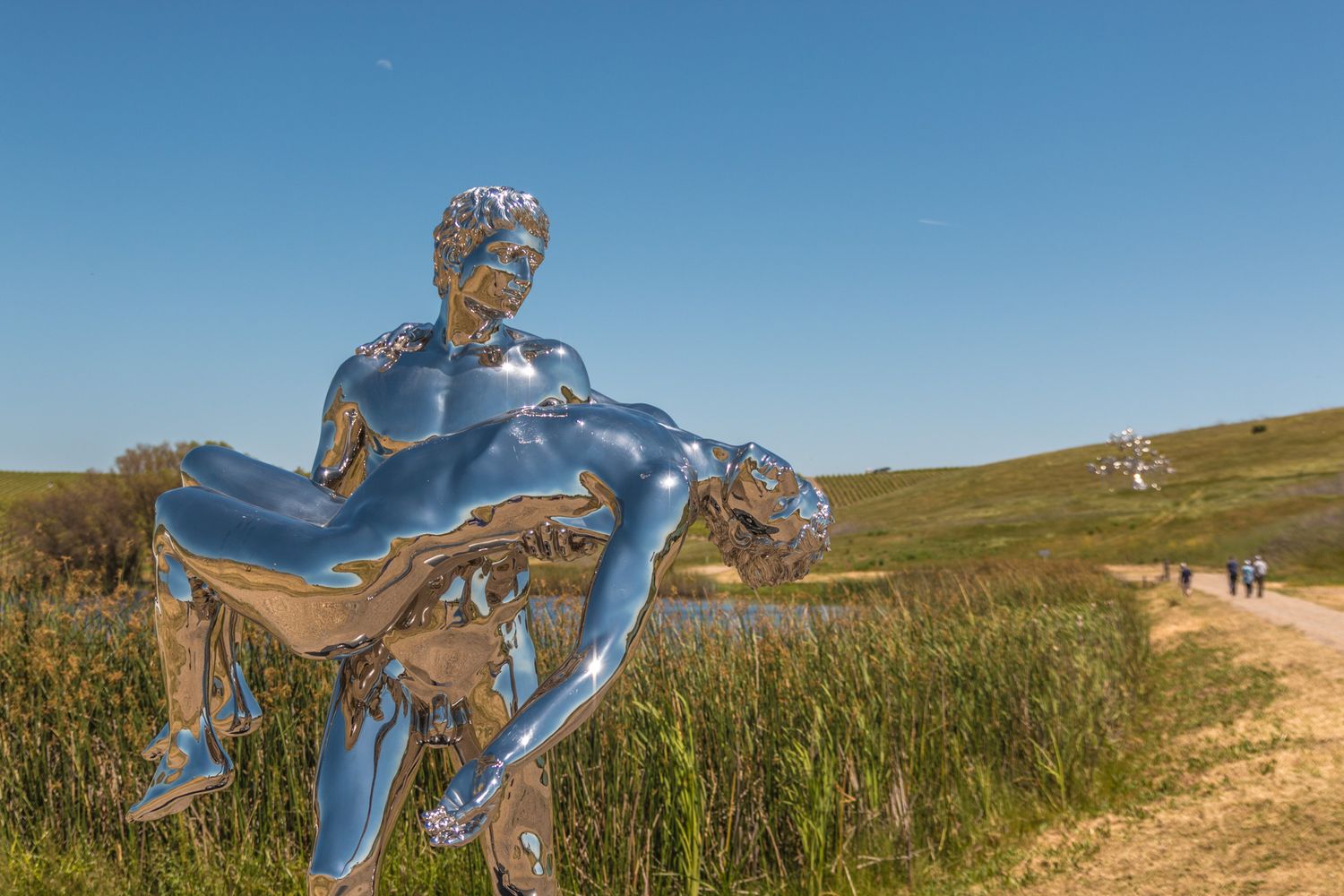Modern metallic blue sculpture installation displayed against rolling hills landscape.