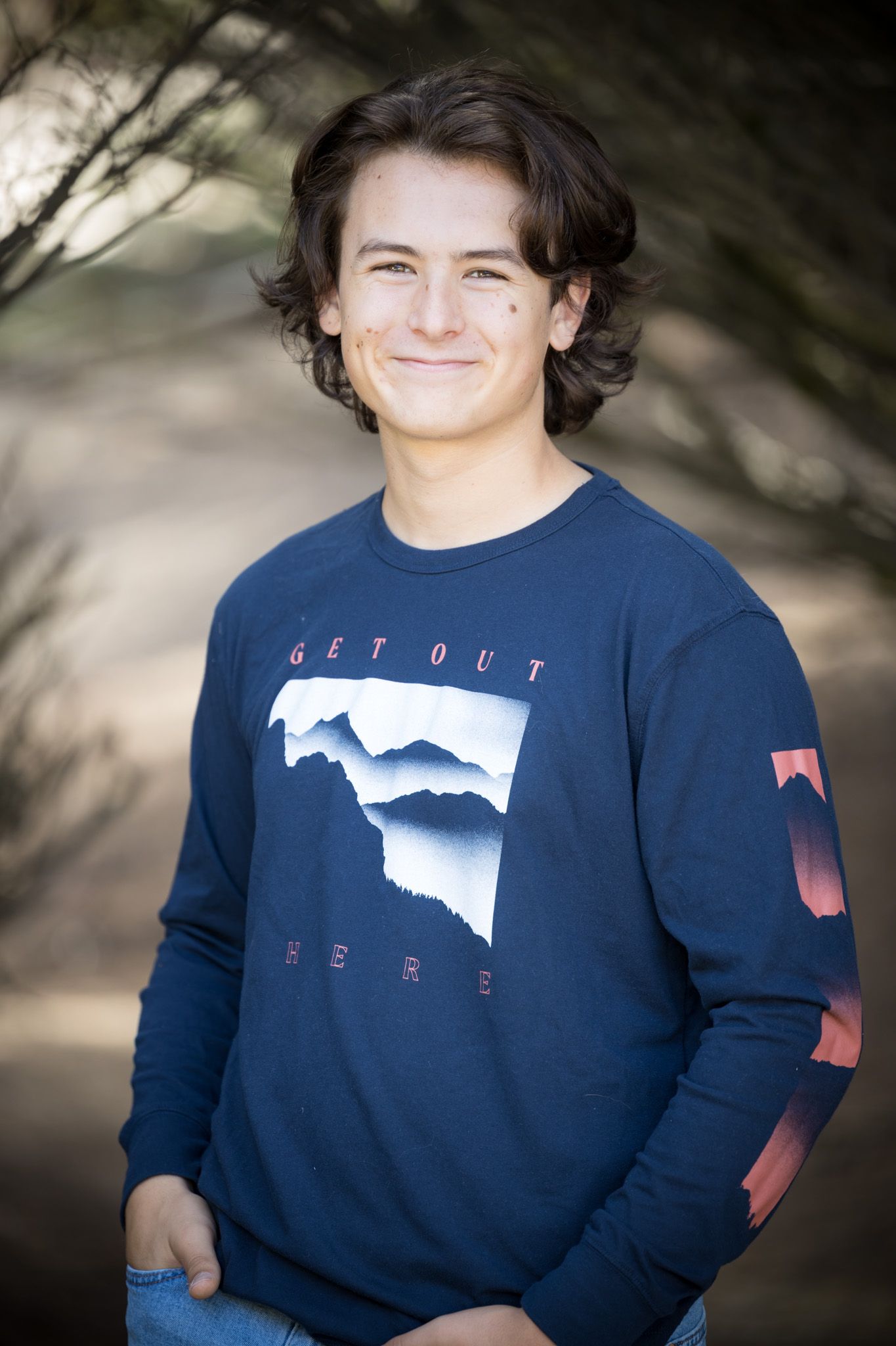 Portrait in navy graphic sweatshirt against natural background.