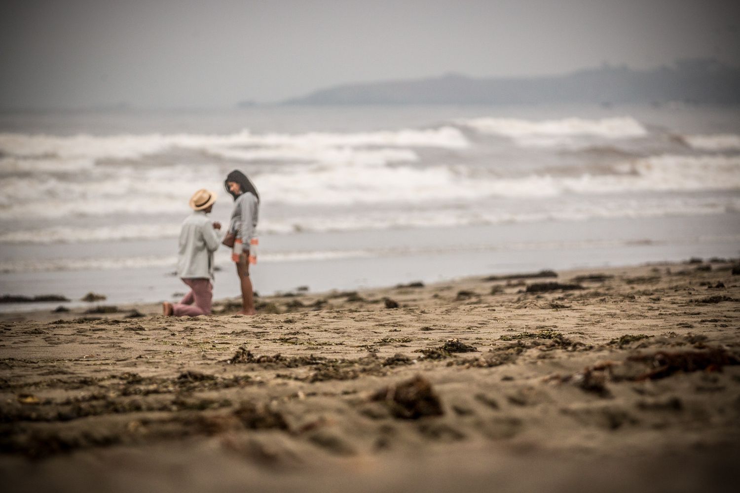 Small silhouettes on vast beach with ocean waves rolling in.