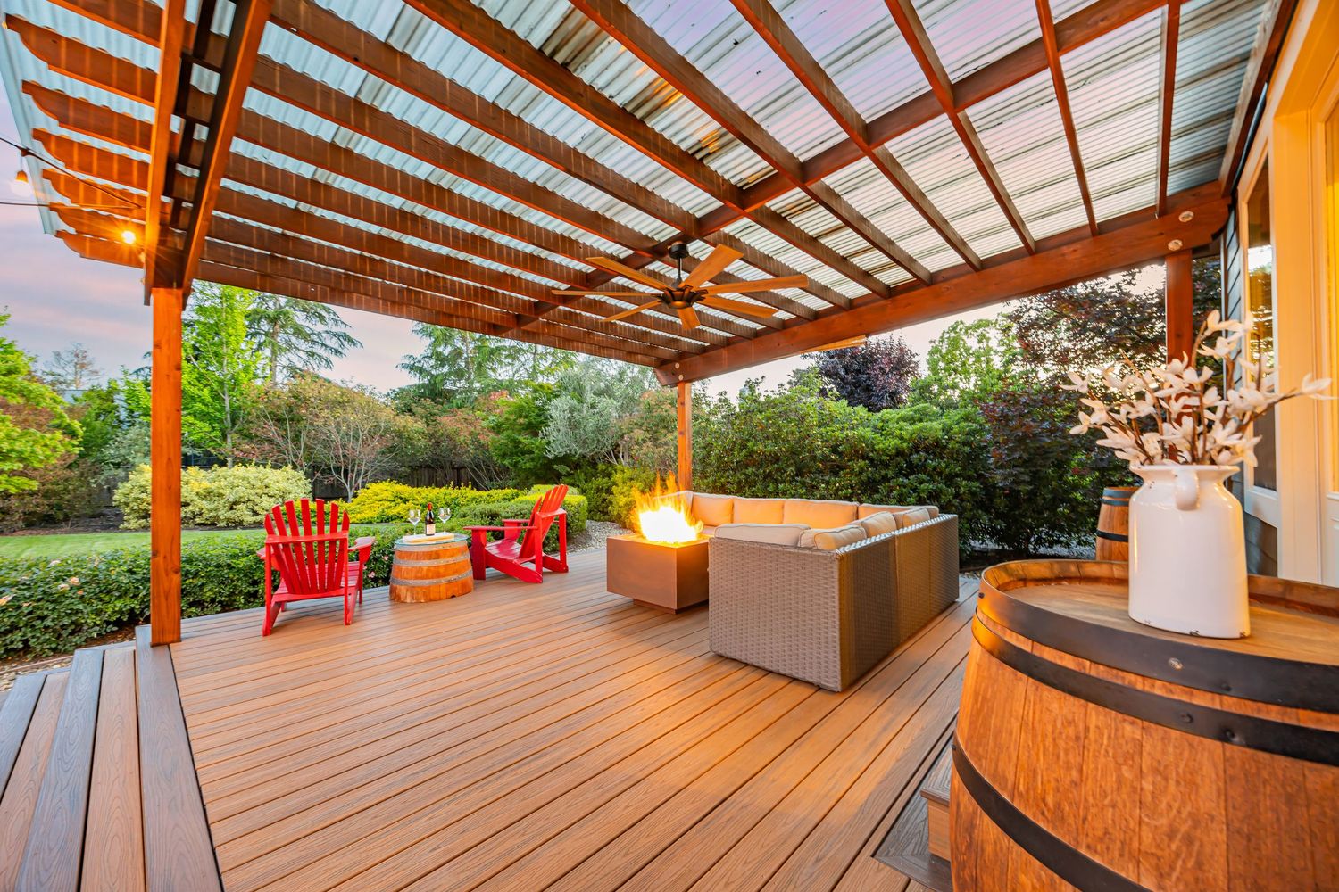 Spacious covered deck featuring red Adirondack chairs and contemporary outdoor seating under wooden beams.
