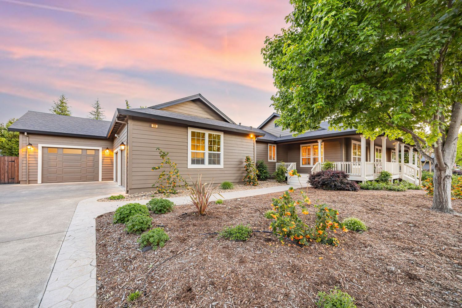 Modern ranch home exterior with fresh landscaping and attached garage at sunset.