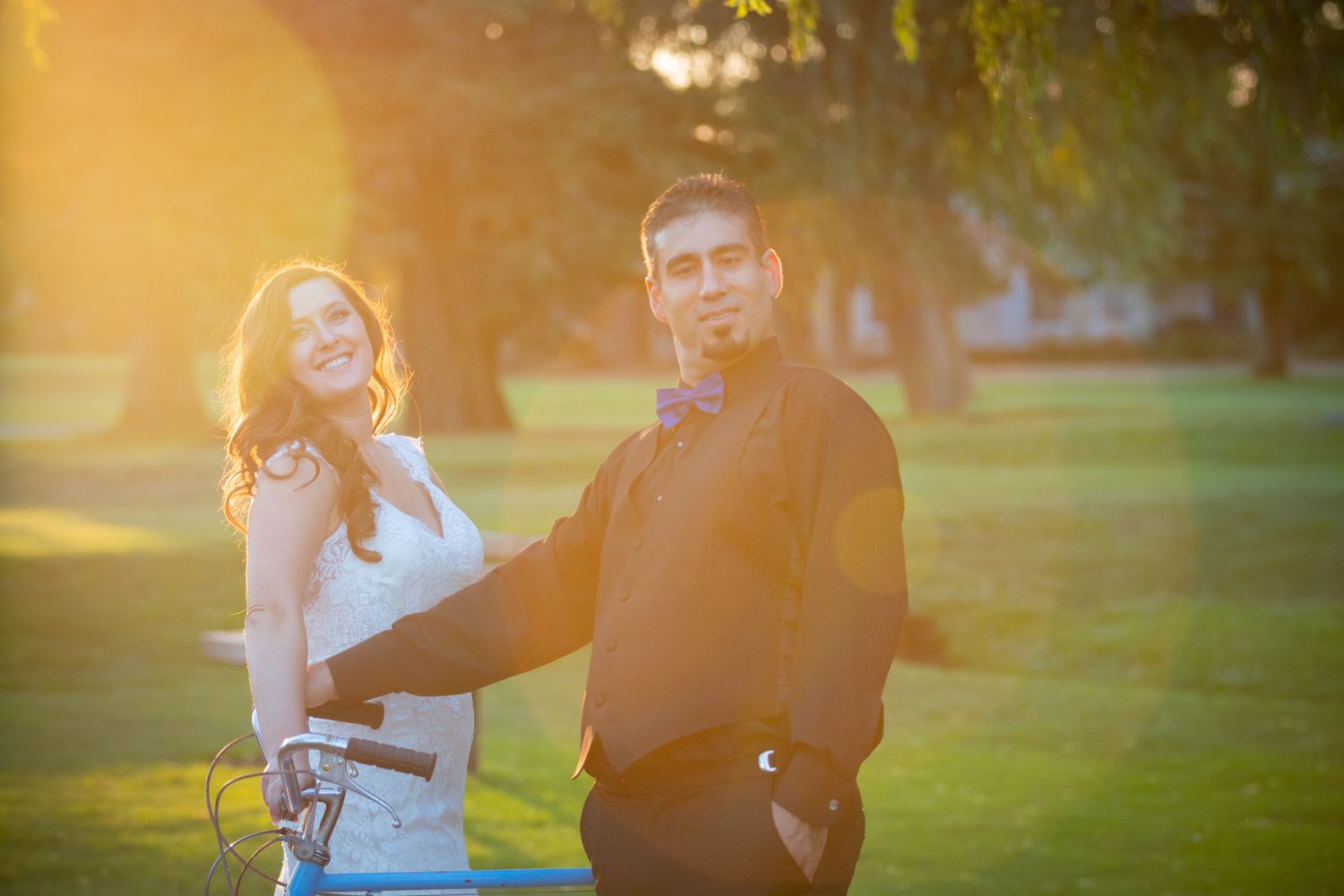 Casual wedding portrait with couple laughing in warm sunset lighting.
