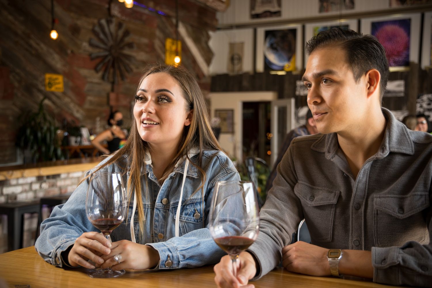 Two people chatting over drinks at a cozy restaurant with decorative wall art.