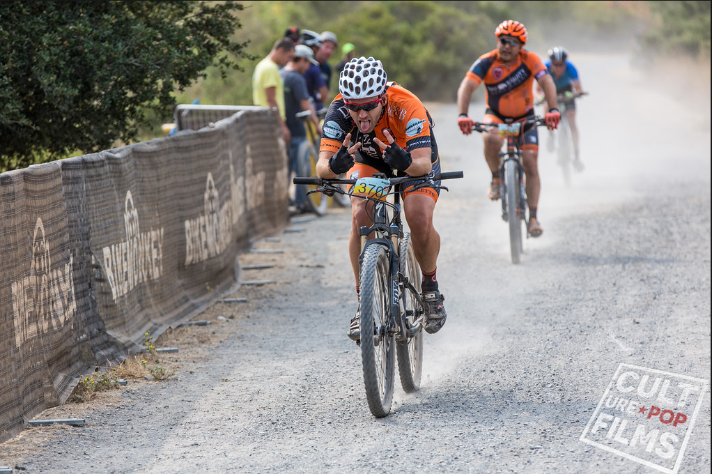 Cyclists racing on a dusty gravel road during an outdoor competition.