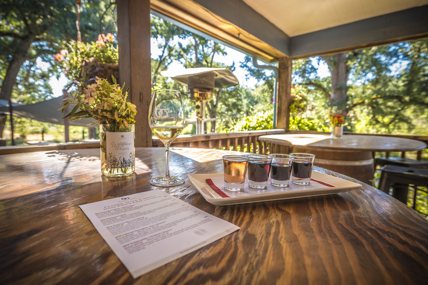 Beer flight tasting setup on wooden table with scenic mountain views through window.