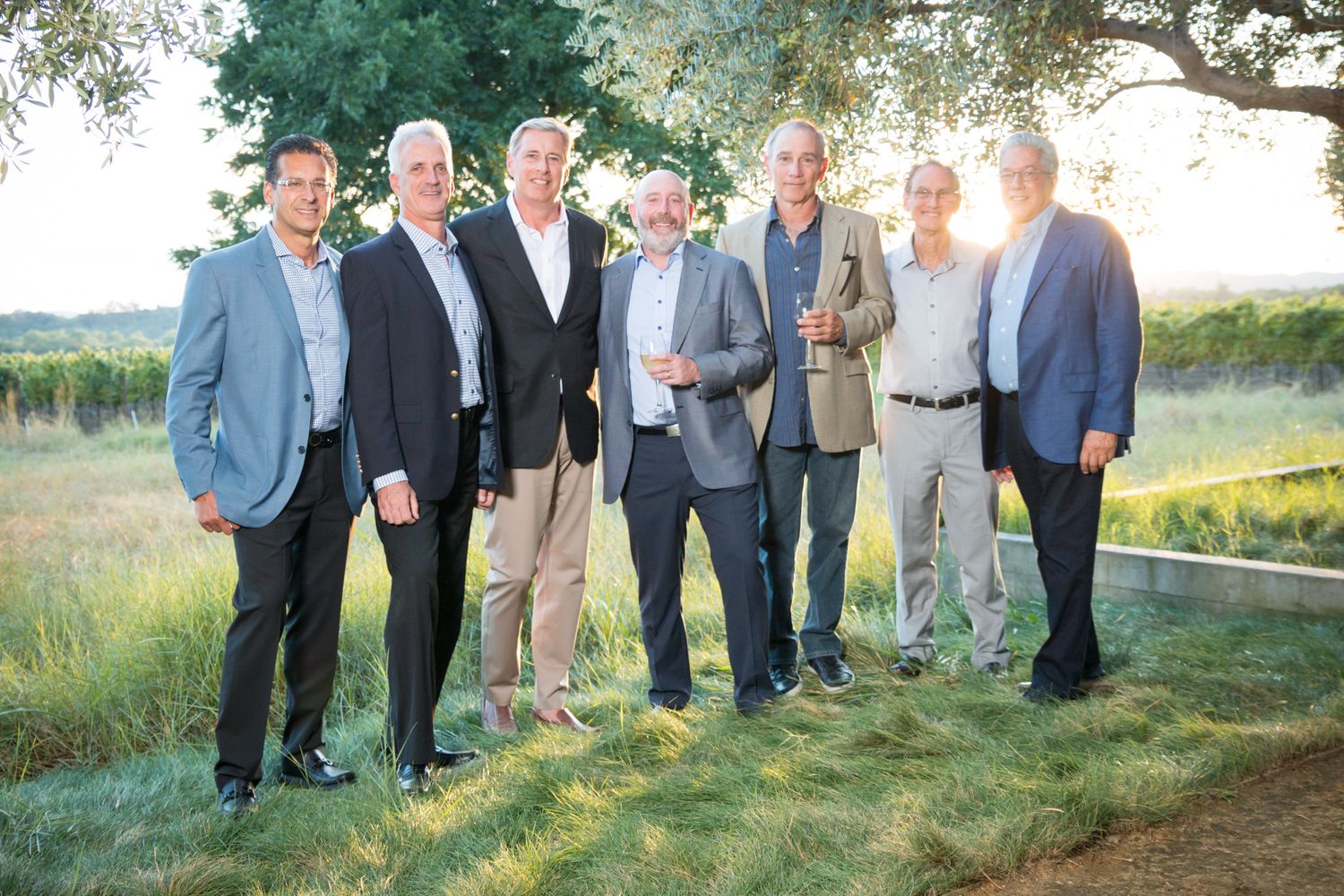 Professional group gathering outdoors in business attire at dusk.