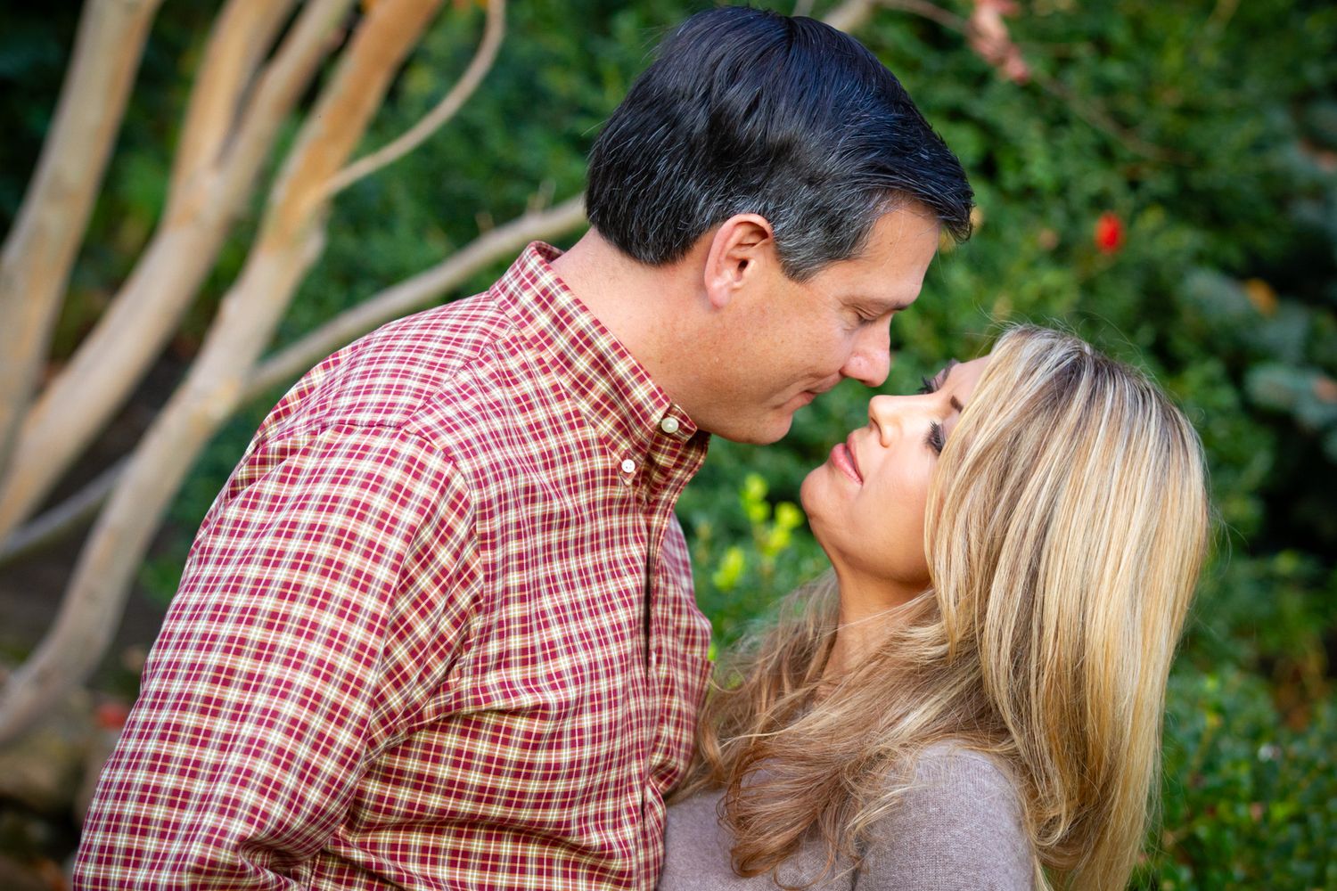 Intimate moment between couple sharing loving gaze outdoors in garden setting.