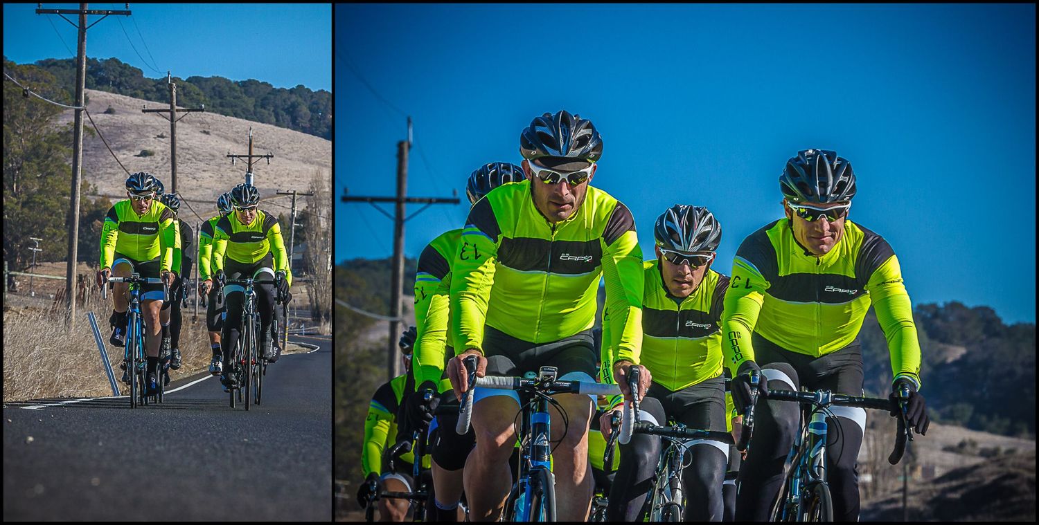 Team of cyclists in matching hi-vis yellow jerseys pedaling through desert landscape.