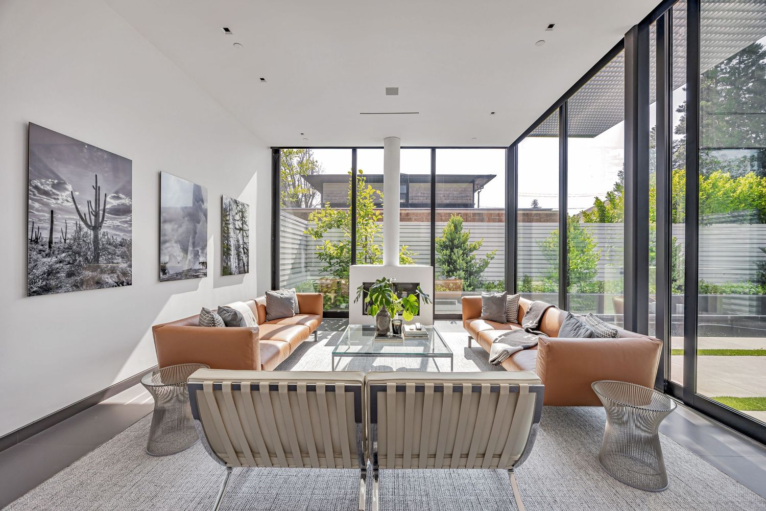 Contemporary living space with leather seating, black and white photography, and large glass windows.