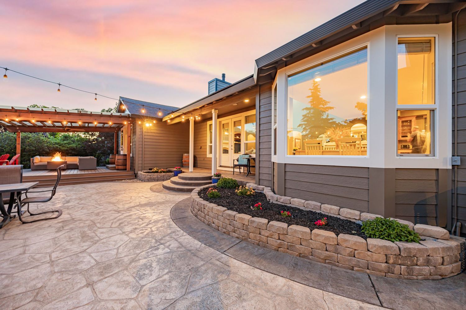 Contemporary home with landscaped stone retaining walls and stamped concrete patio at sunset.