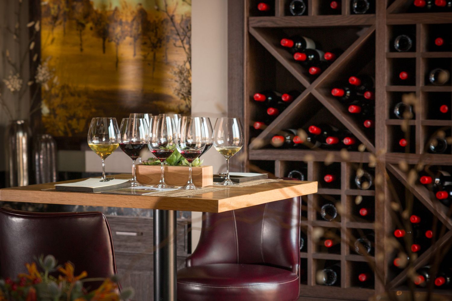 Elegant wine glasses on table with wine rack display and leather seating in restaurant interior.