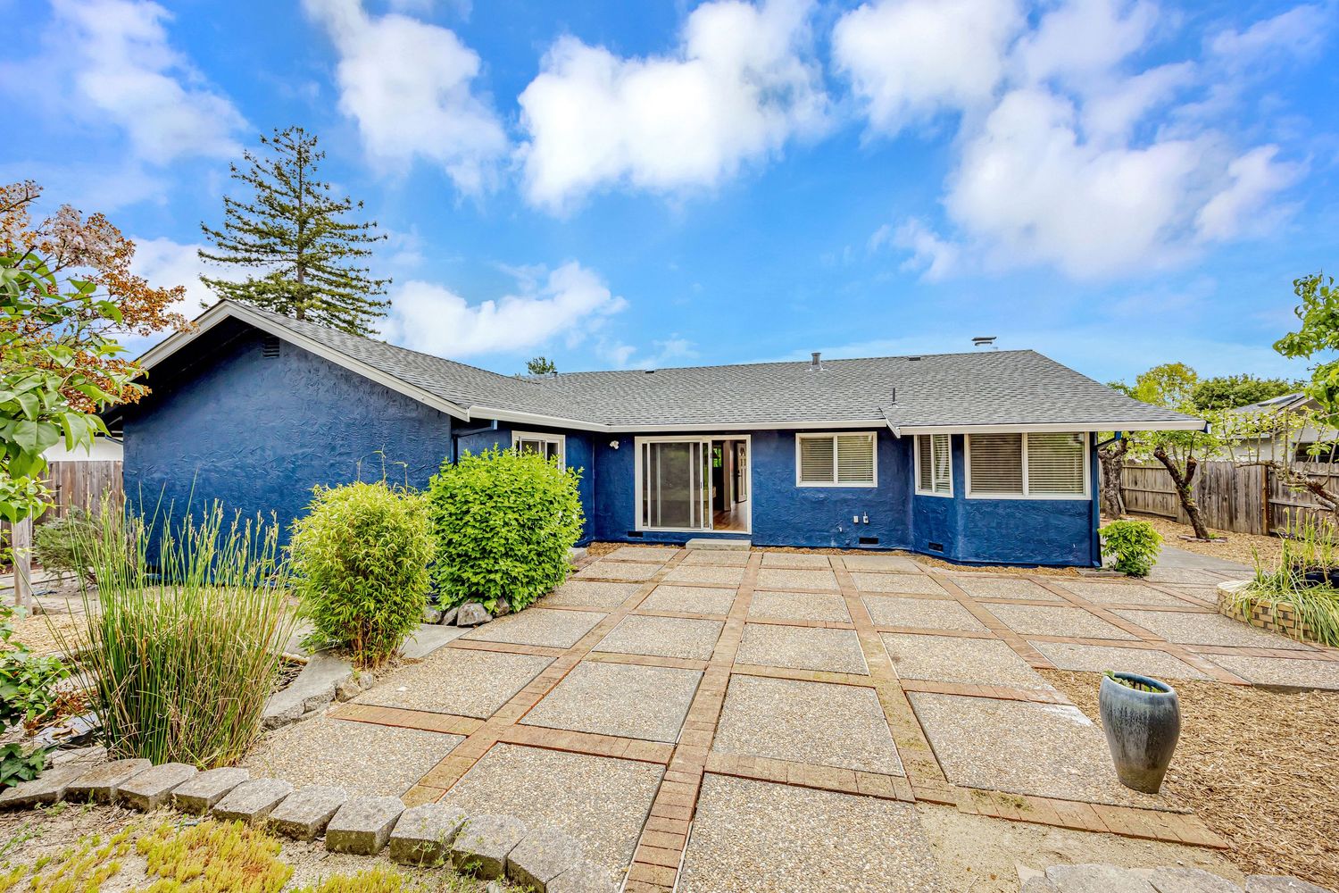 Front view of blue ranch-style home with geometric concrete pathway and landscaped yard.