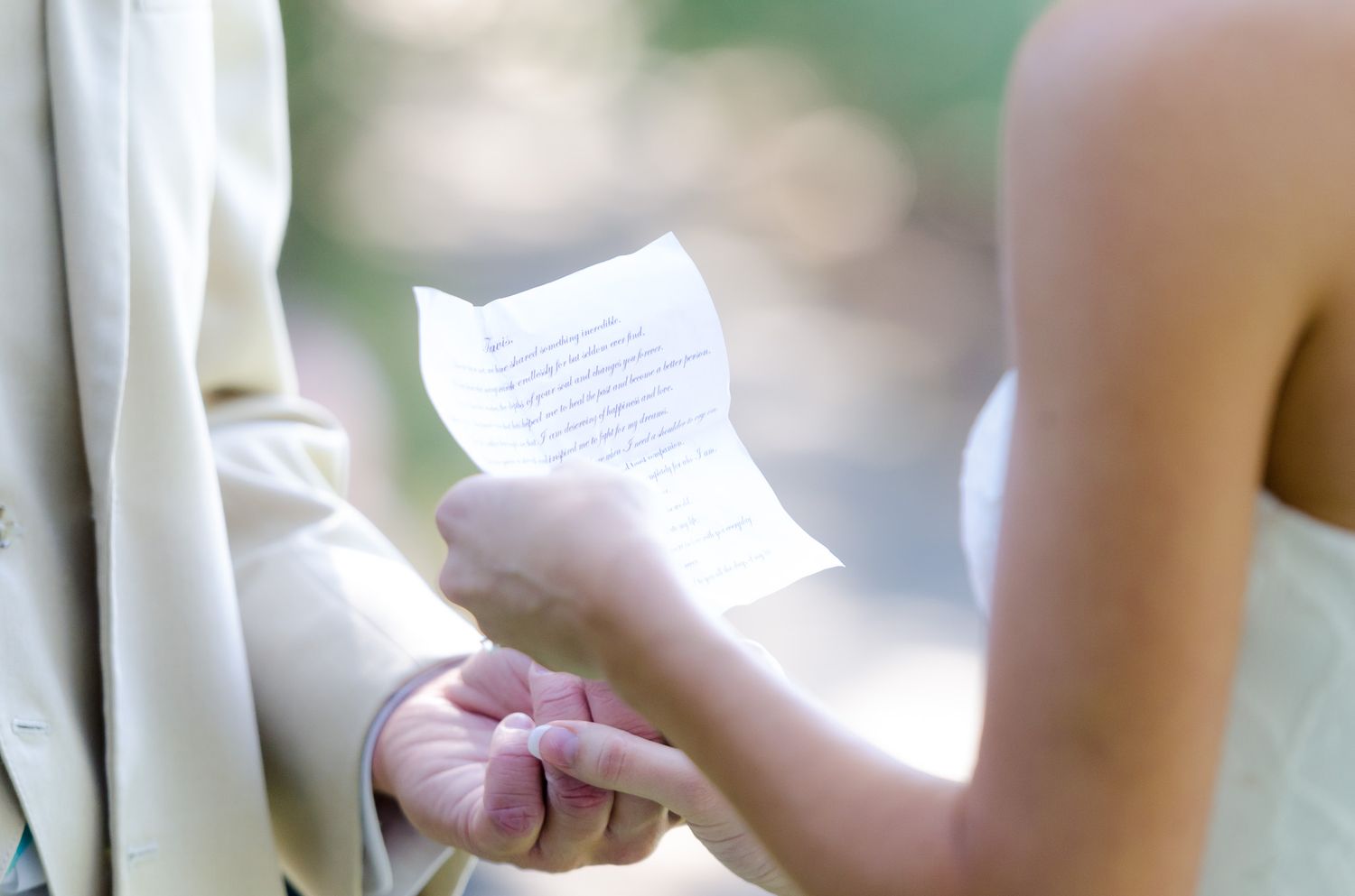 A close-up view of hands holding a handwritten note in soft natural lighting.