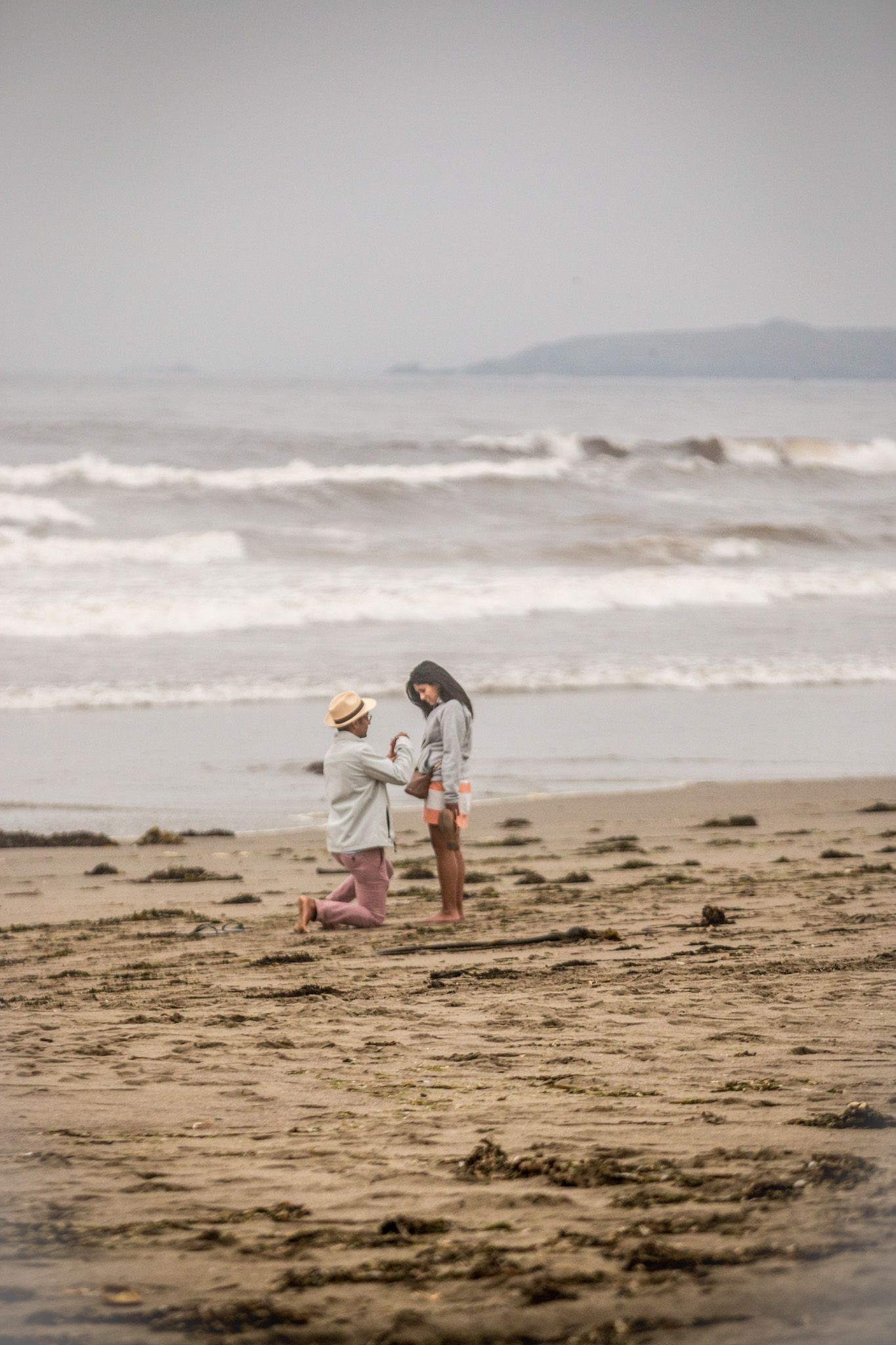 Two figures walking along misty beach shoreline collecting items.